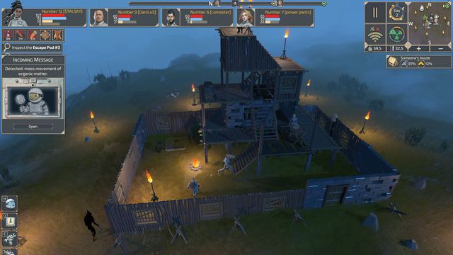 A walled wooden base lit by torches at dusk